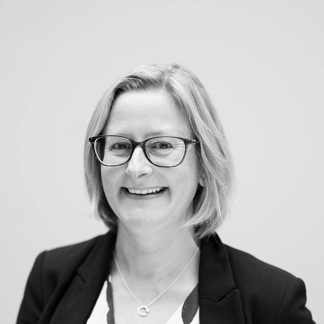 A black and white headshot of a smiling woman