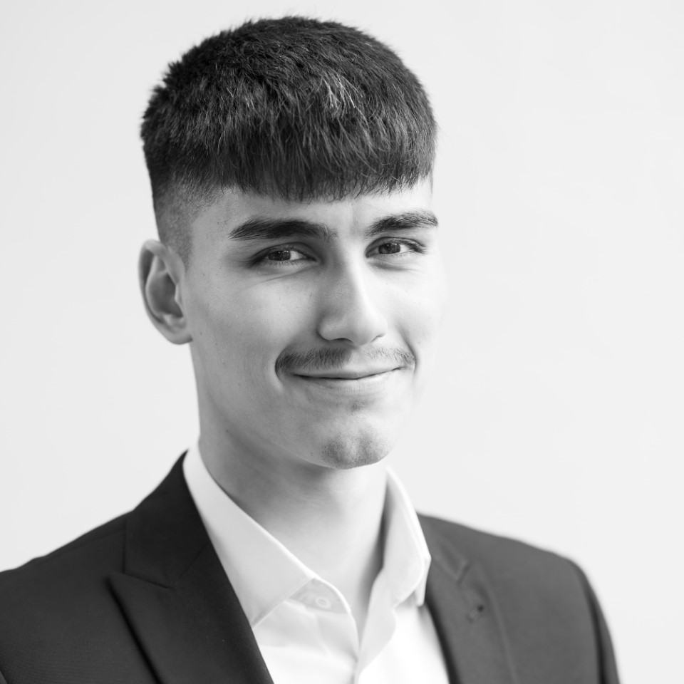 A black and white headshot image of a smiling man against a white backdrop
