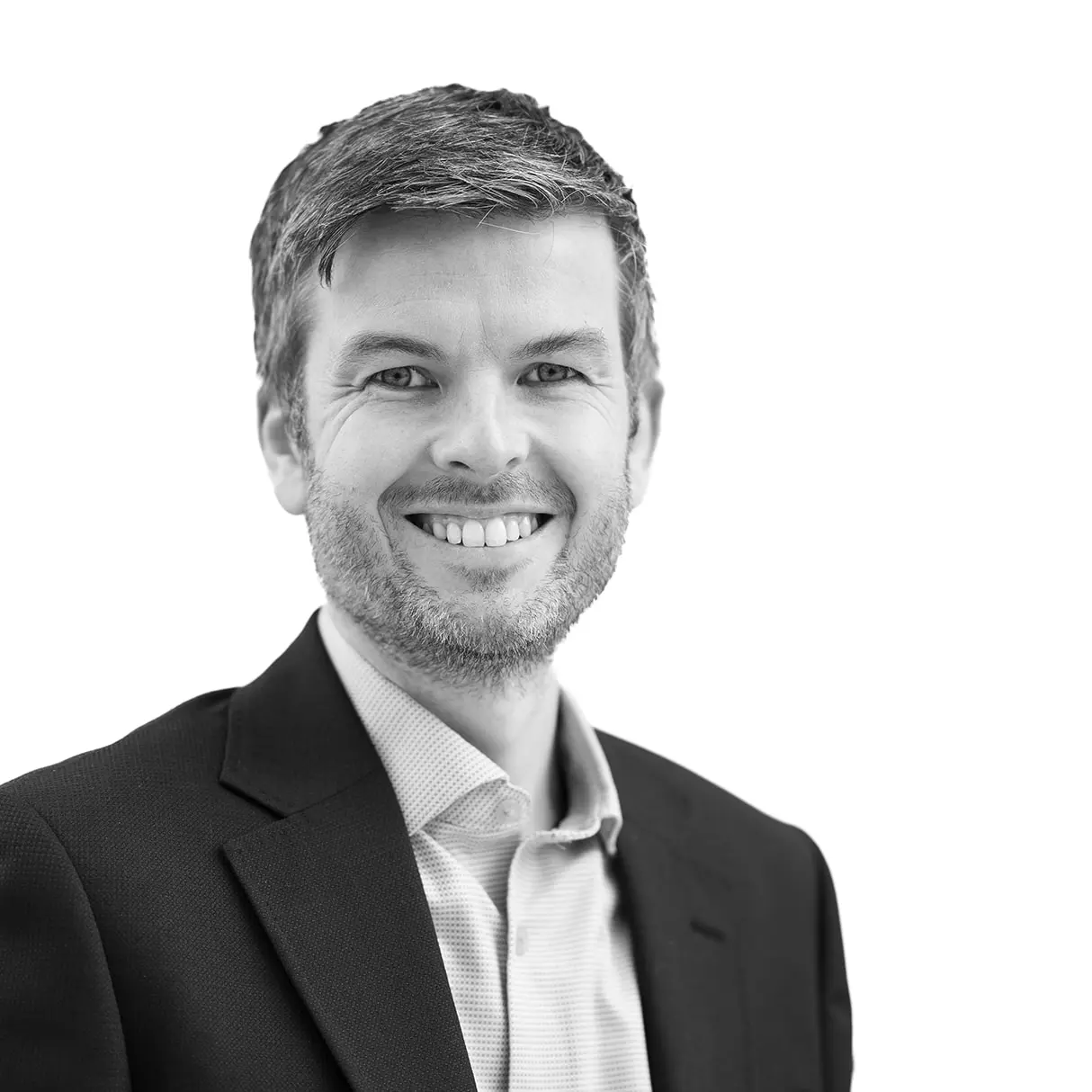 A black and white headshot image of a smiling man against a white backdrop