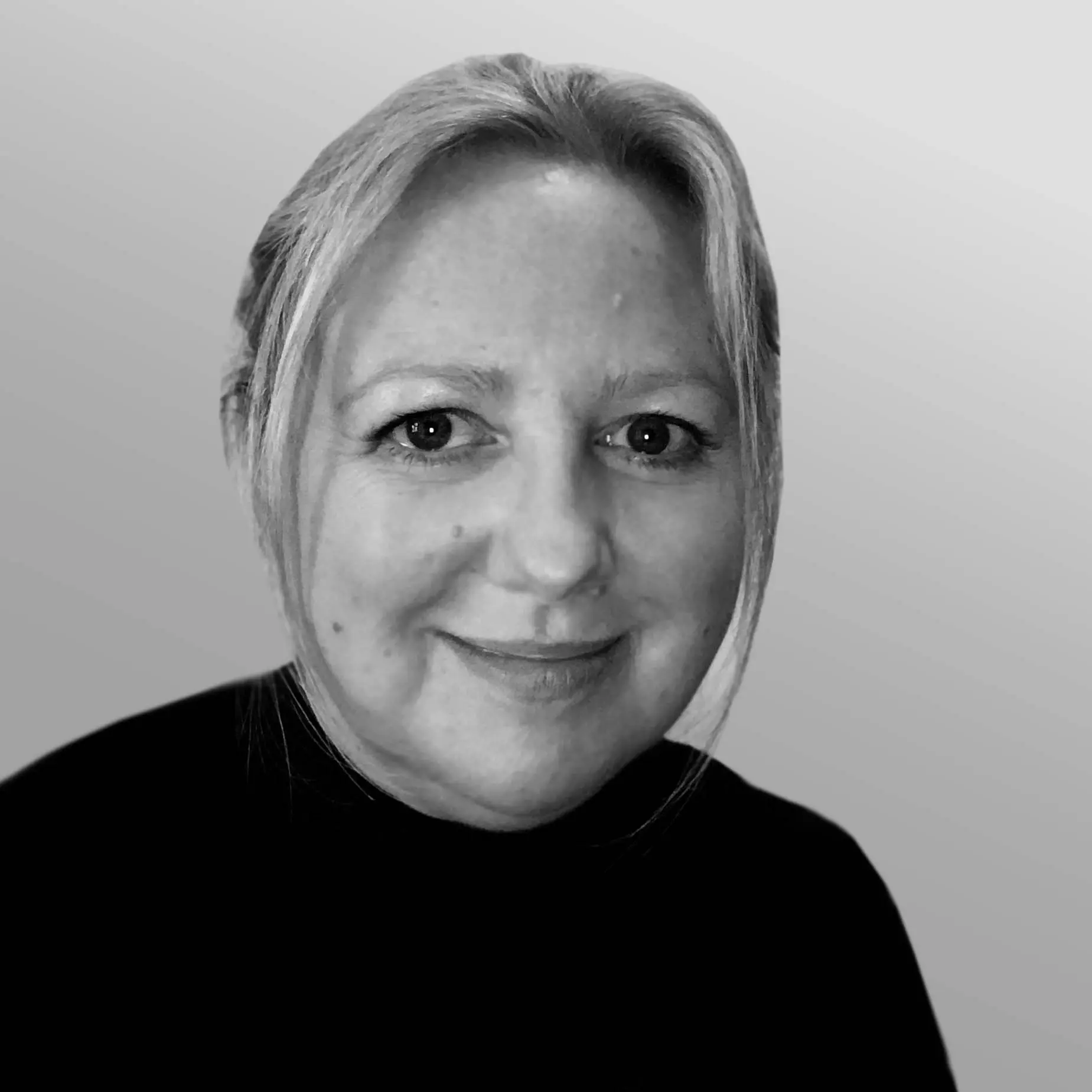 A black and white headshot image of a smiling woman against a white backdrop