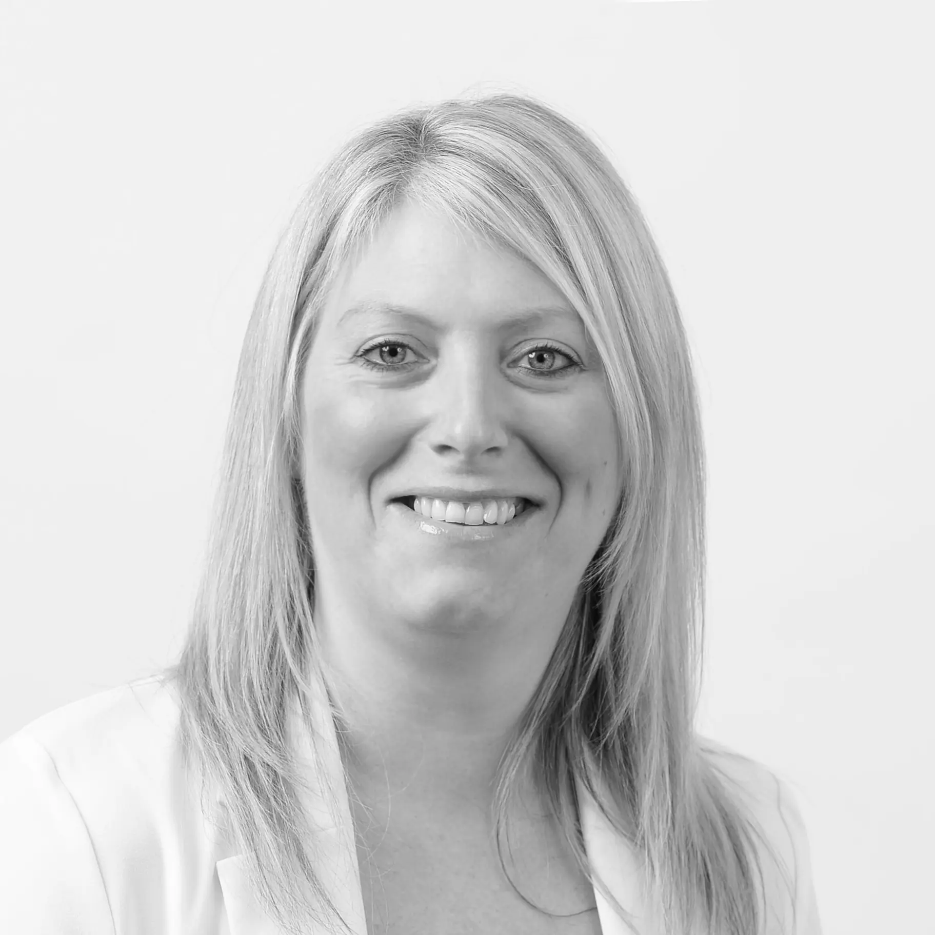 A black and white headshot image of a smiling woman against a white backdrop