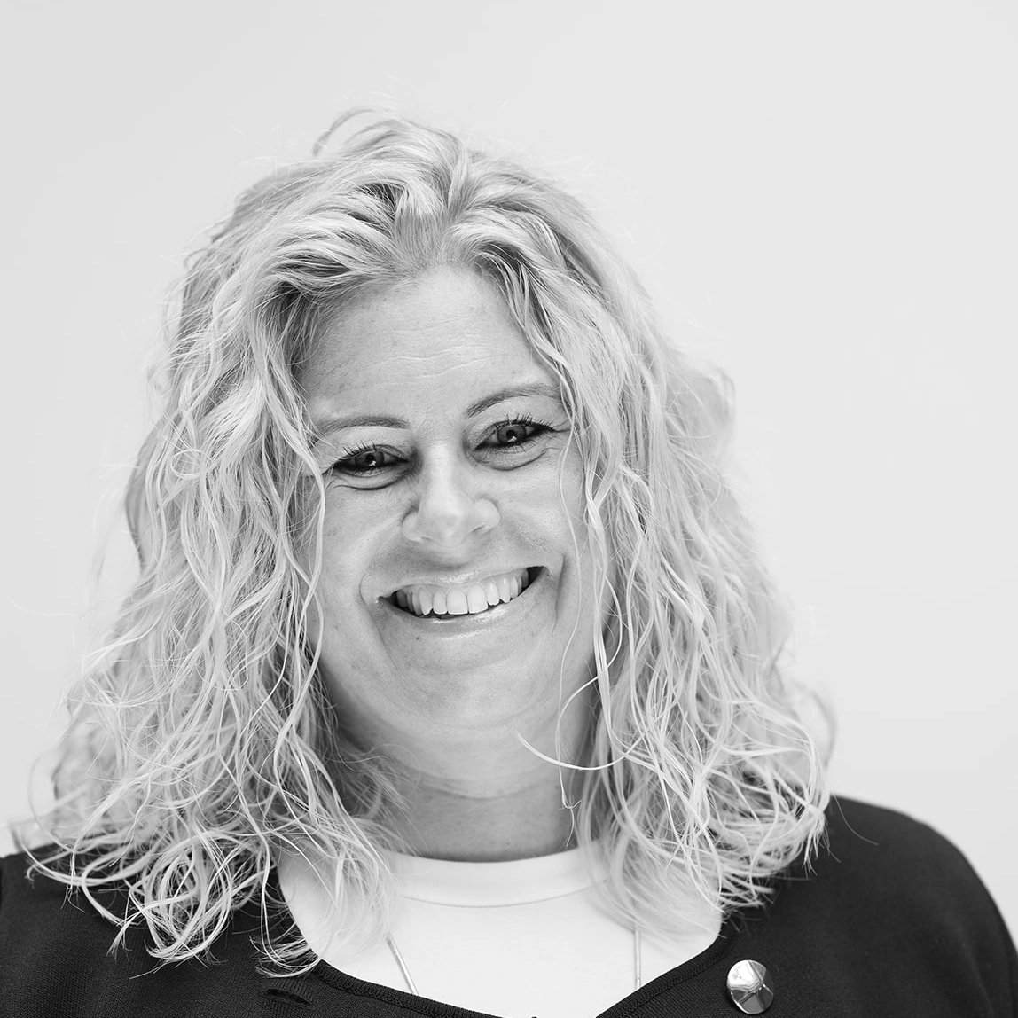 A black and white headshot image of a smiling woman