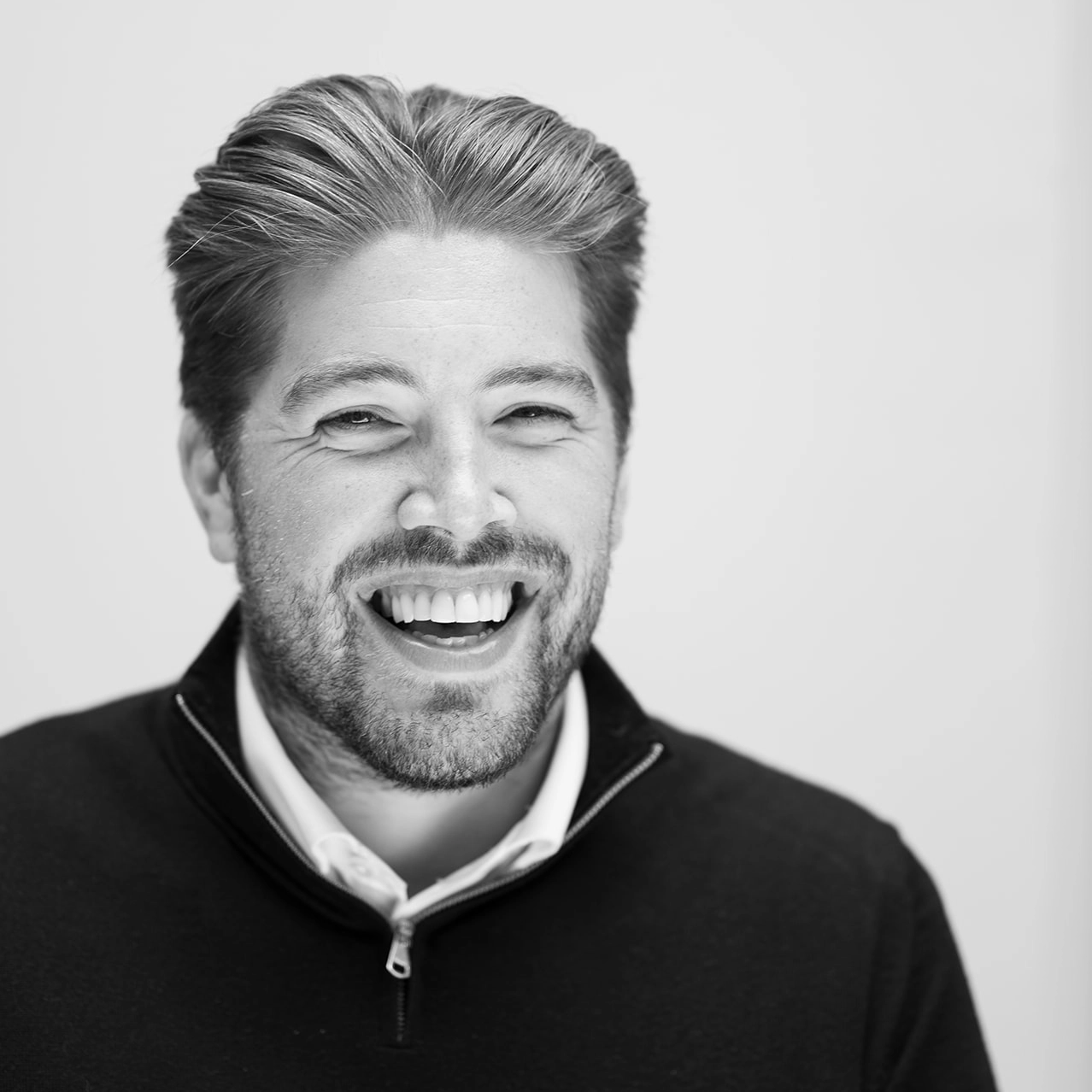 A black and white headshot of a smiling man