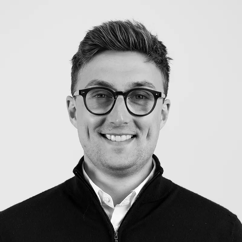 A black and white headshot image of a smiling man against a white backdrop