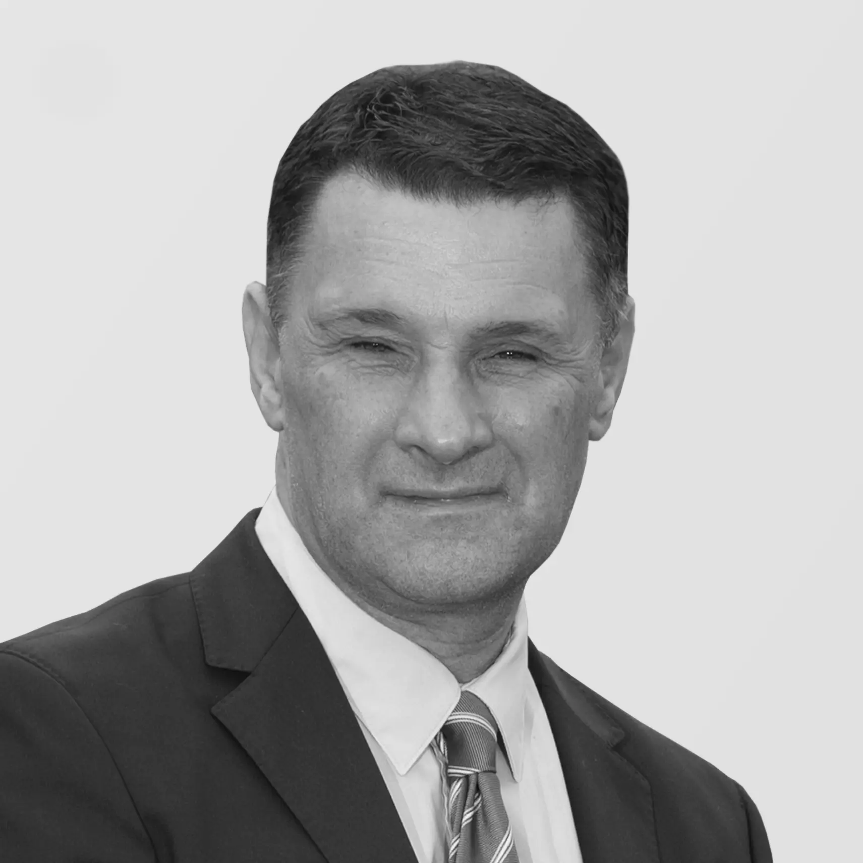 A black and white headshot image of a smiling man against a white backdrop