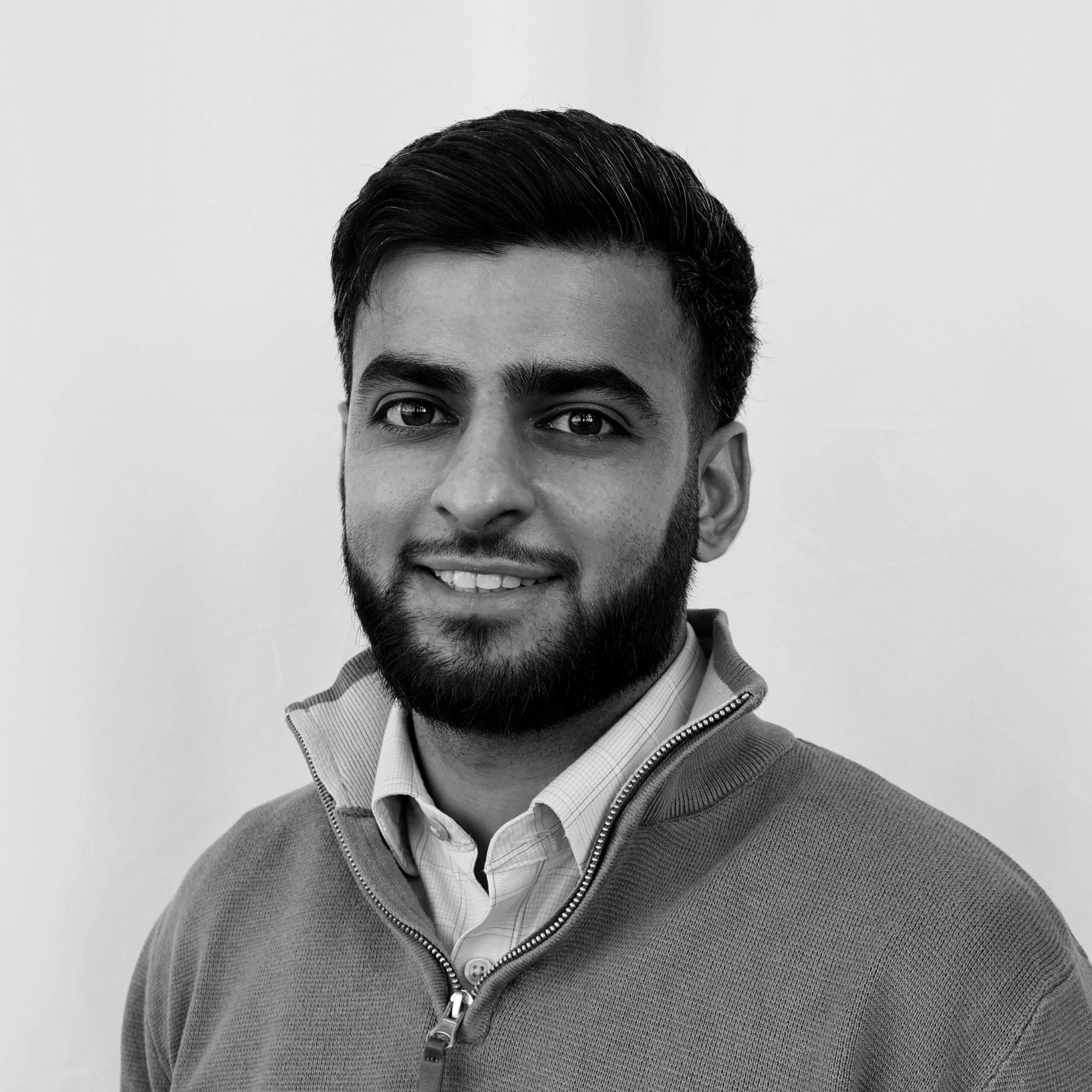 A black and white headshot image of a smiling man against a white backdrop