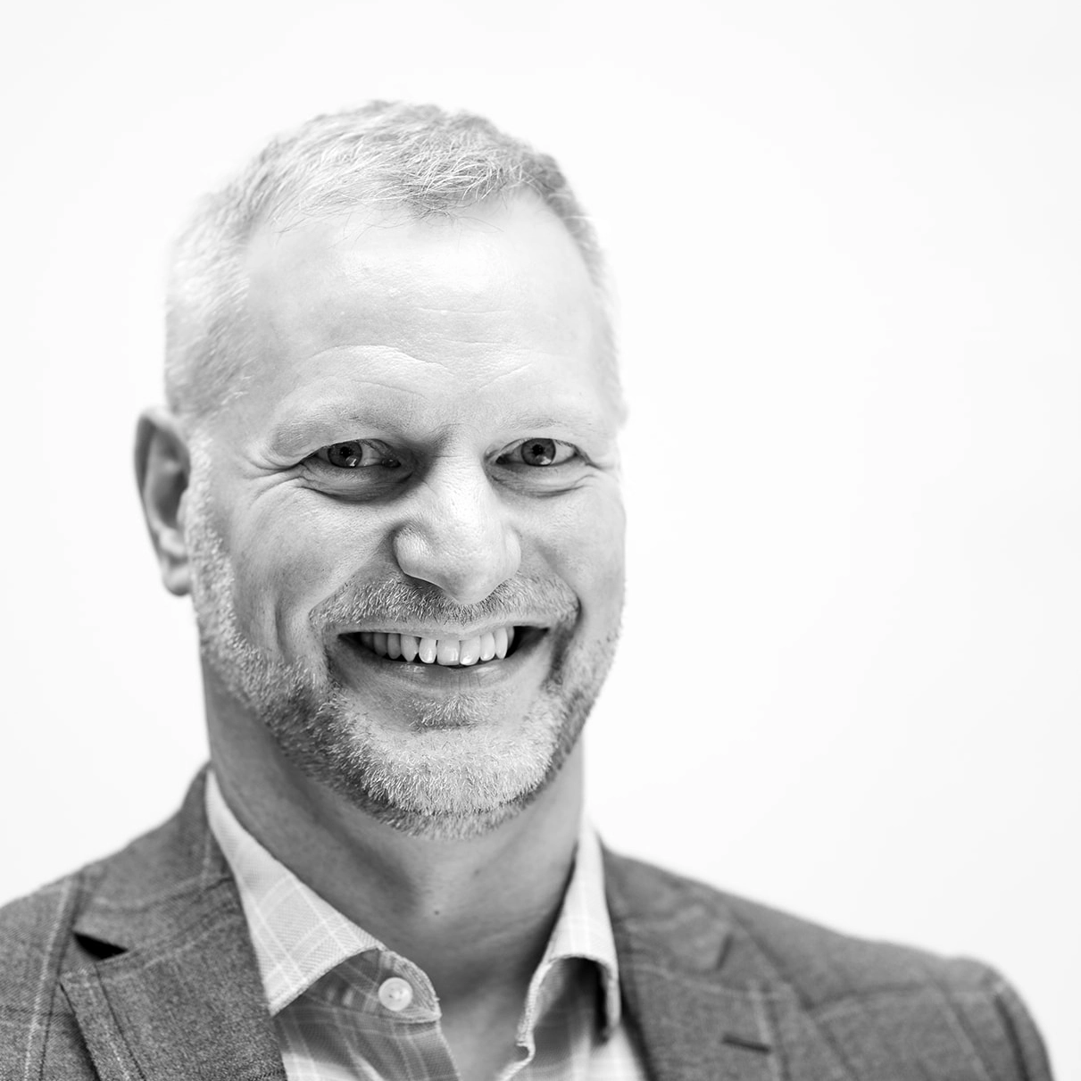 A black and white headshot image of a smiling man