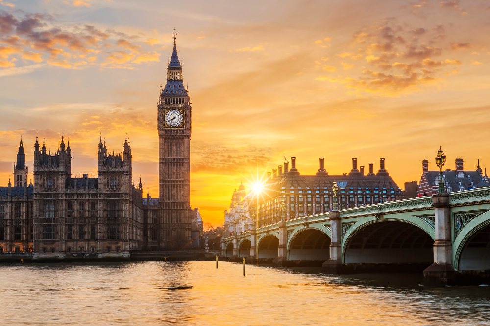 A zoomed-out shot of Big Ben and the Thames River in London during sunset.