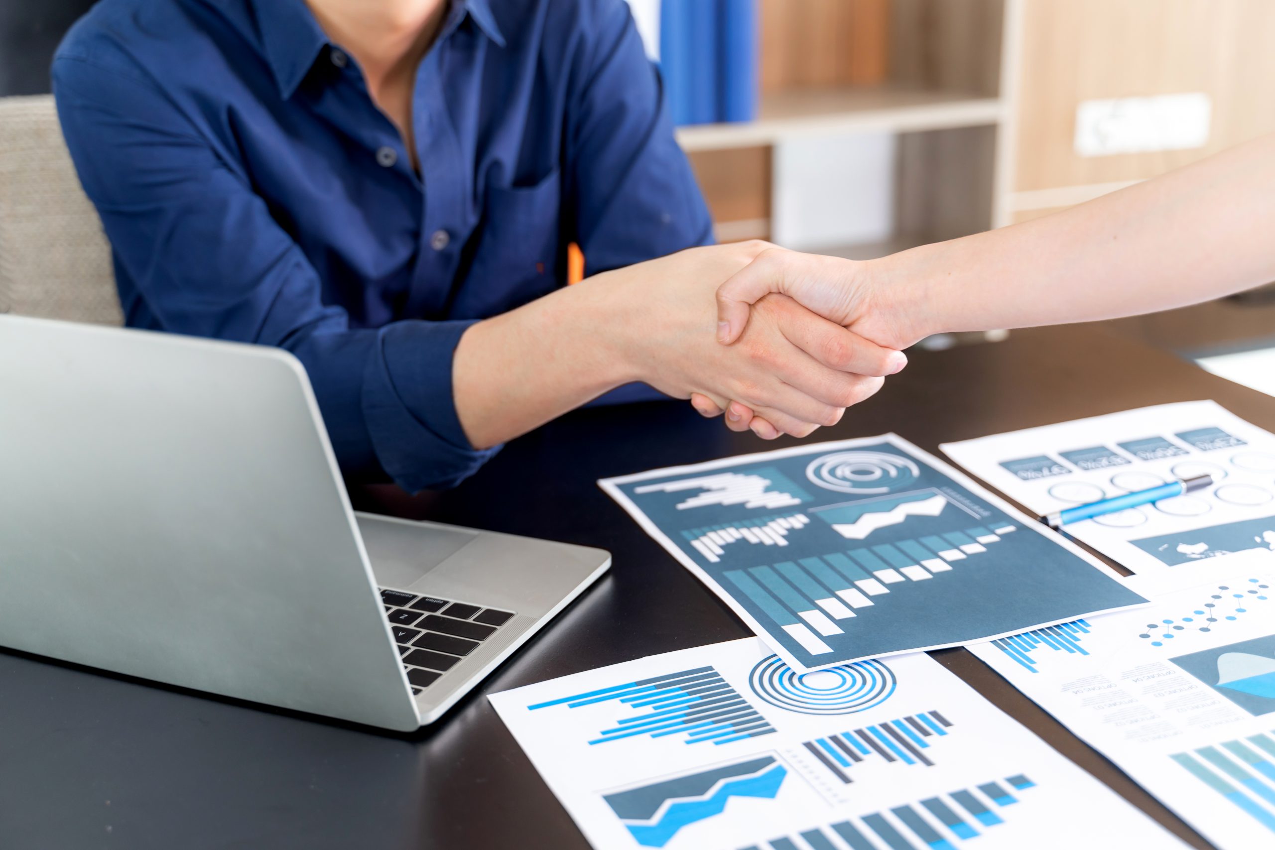 A young male professional shakes hand with another professional in an office.