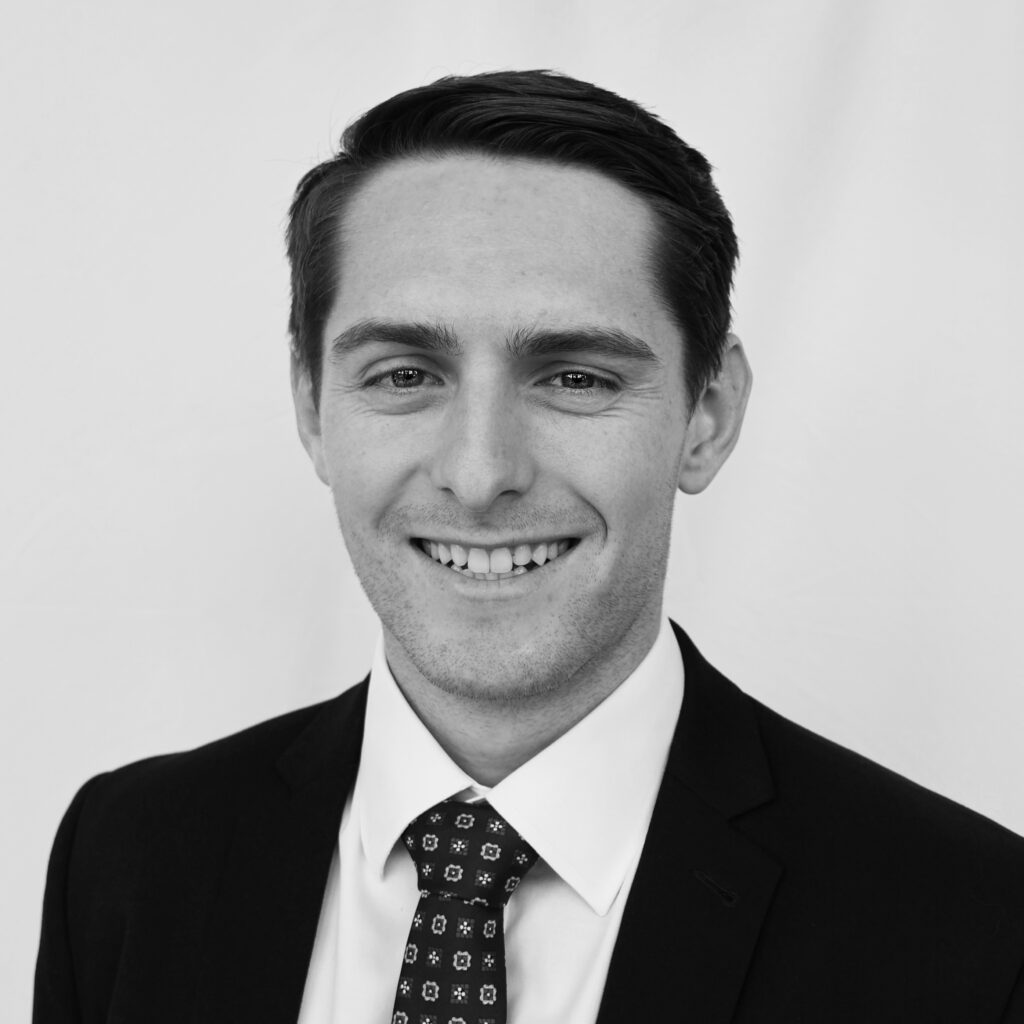 A black and white headshot of a smiling man