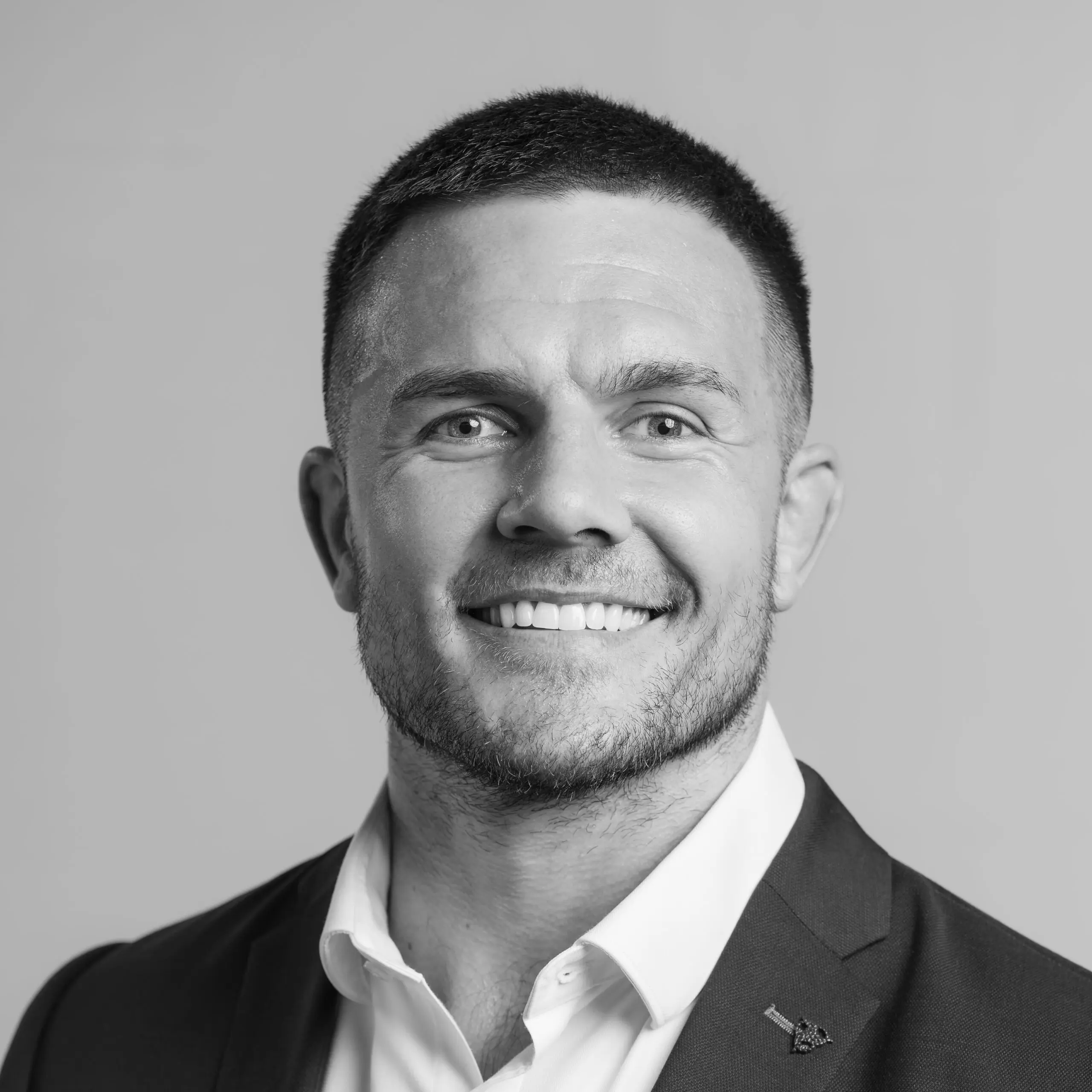 A black and white headshot of a smiling man