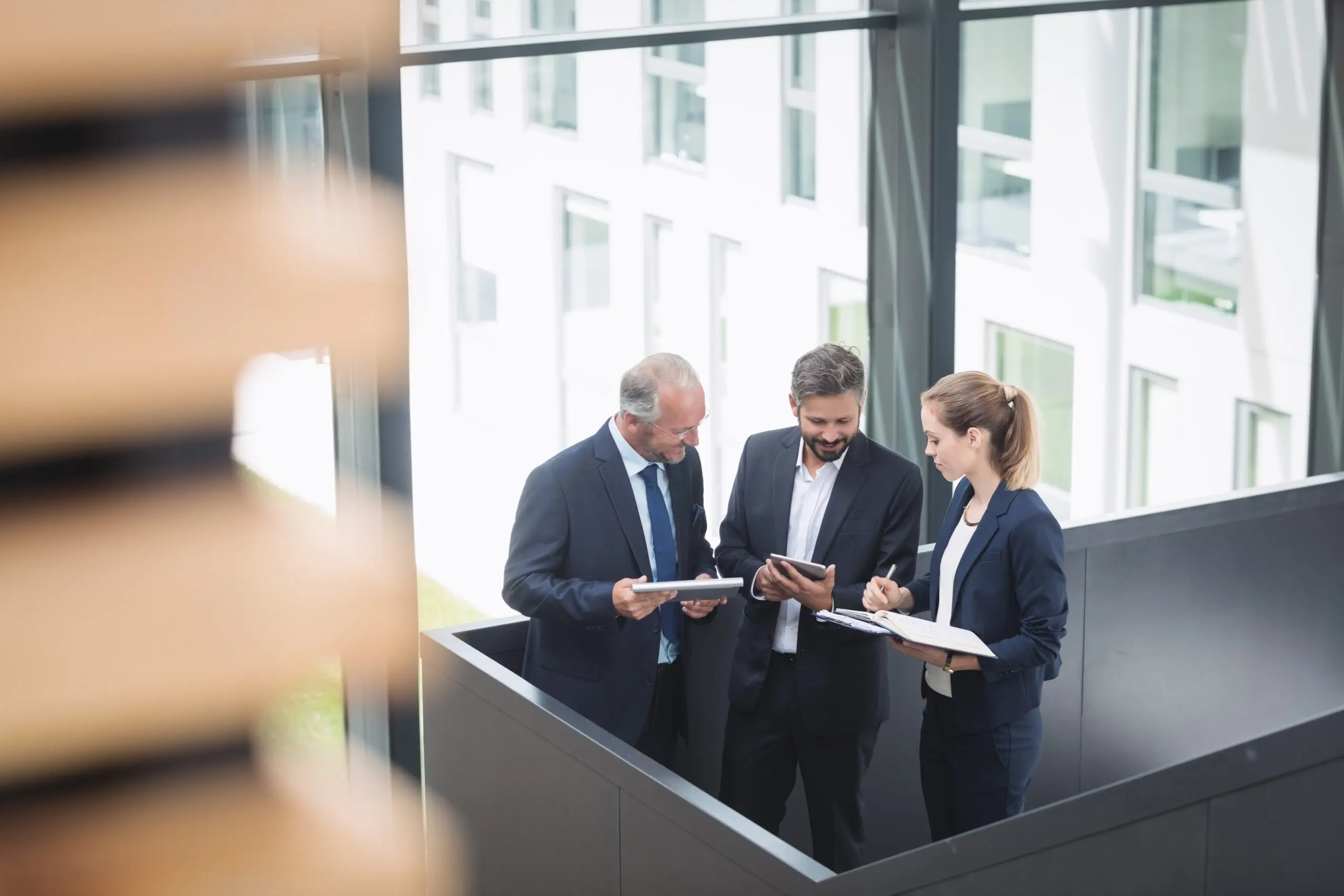 Group of businesspeople having a discussion near staircase in office